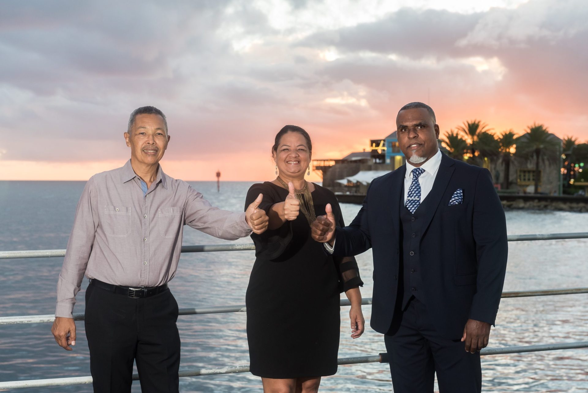 Three professional people on the bridge smiling and giving a thumbs up